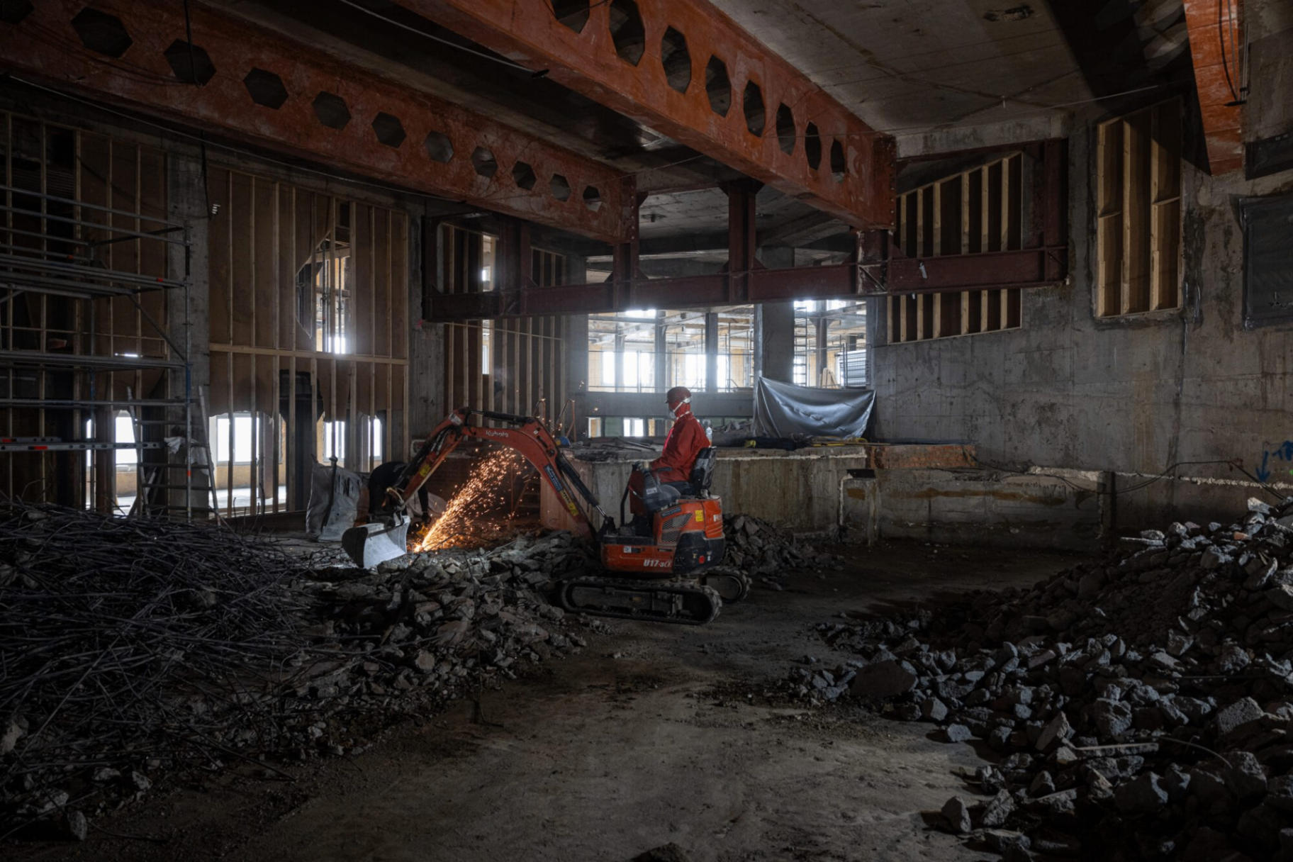 Graafmachine aan het werk tussen puin en betonnen structuren in de Boerentorenwerf.